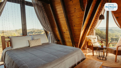 Chambre de chalet en bois sous les combles avec un grand lit et vue sur la montagne